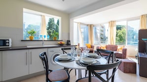 A modern kitchen with a dining area, large windows, and a view of greenery. - Bright 2-Bedroom Apartment – Close to La Croisette & City Centre (Cannes)