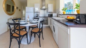 A modern kitchen with a dining area, a washing machine, and a window with a view. - Bright 2-Bedroom Apartment – Close to La Croisette & City Centre (Cannes)