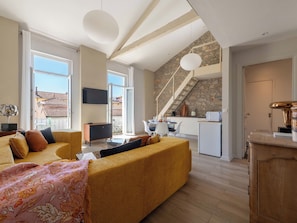 Ein modernes Wohnzimmer mit Sofa, Essbereich, Küche und einer Treppe.