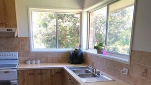 A kitchen with a large island, two stools, a sink, and a stove. - Pet Friendly Coastal Stay Near The Beach. (Bundaberg)