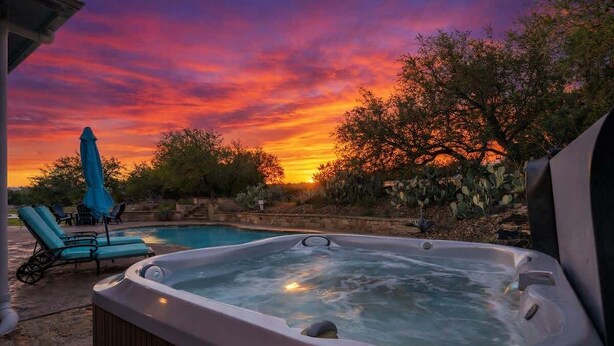 A hot tub with a pool, lounge chairs, and a sunset view. - Private 16-Acre Retreat, Pool, Hot Tub & Hill Country Views - Sleeps 16 (Hays County)