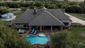 A two-story house with a large swimming pool, a hot tub, and a covered patio area. - Private 16-Acre Retreat, Pool, Hot Tub & Hill Country Views - Sleeps 16 (Hays County)