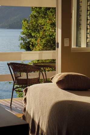 A room with a bed, a chair, and a view of a lake. - Papiro Hotel Boutique E Restaurante (Angra dos Reis)
