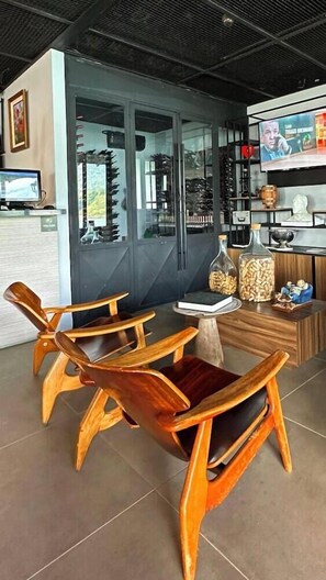Um interior moderno com cadeiras de madeira, uma pequena mesa e uma televisão na parede.