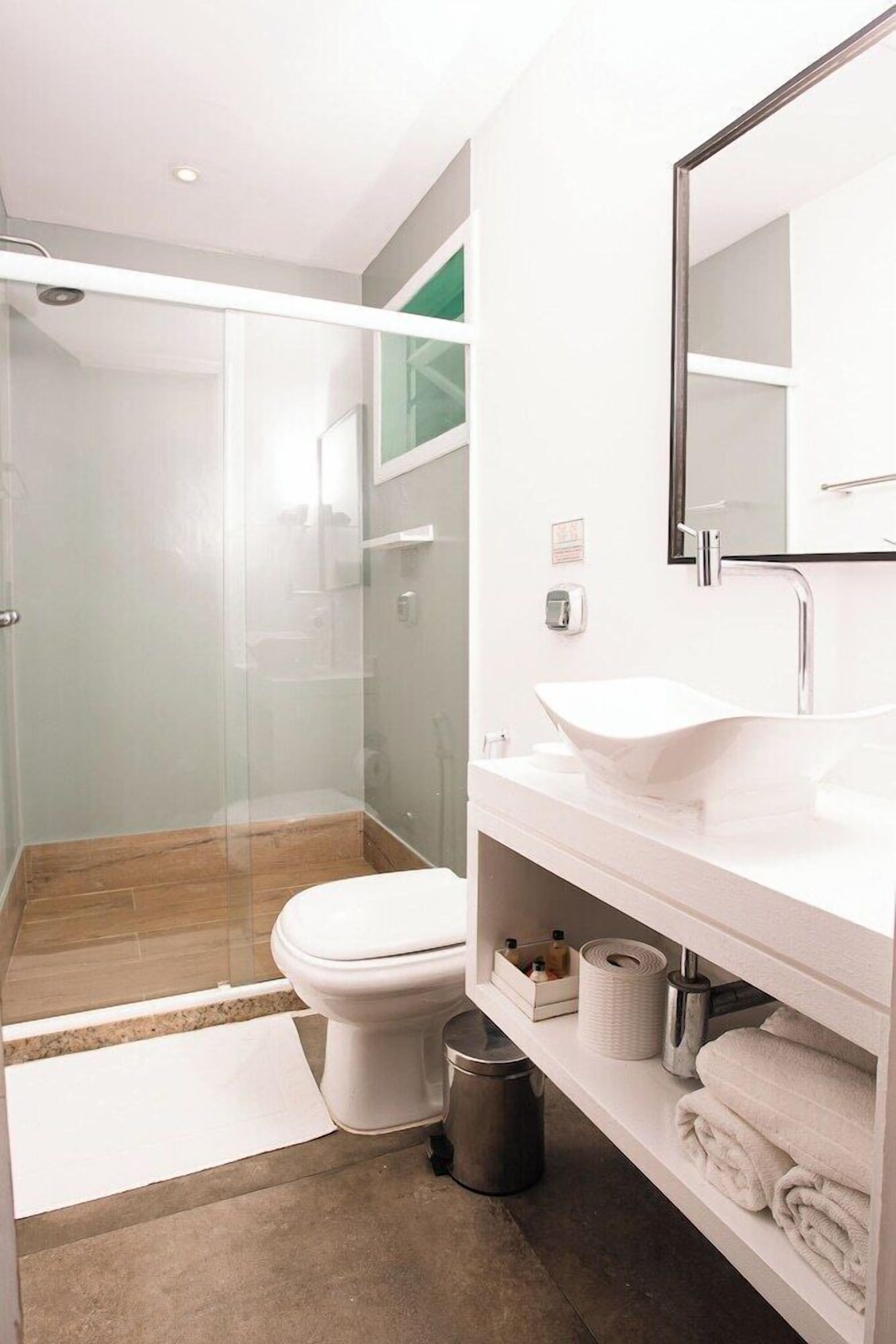 A modern bathroom with a glass-enclosed shower, a white sink, and a mirror above it.