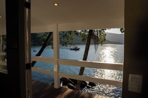 Vista de um quarto com varanda de madeira, dando para um lago com barcos.