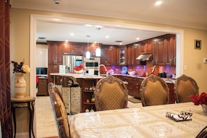 A spacious kitchen with modern appliances, a dining area with a table and chairs, and a view into the adjacent living area. - Fort Washington Retreat - 5 minutes to Gaylord & MGM (Fort Washington)