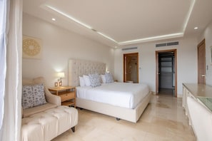 Une chambre moderne avec un grand lit, des tables de chevet, un canapé et un dressing.