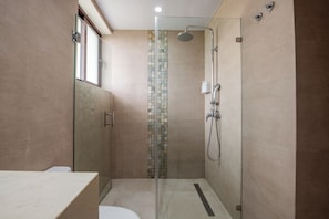 A modern bathroom with a glass shower enclosure, a tiled shower wall, and a toilet. - Hacienda Samana Bay (Samaná)