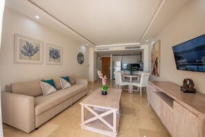 Un salon moderne avec un canapé, une table basse et un téléviseur. Il y a également un coin repas avec des chaises et une table.