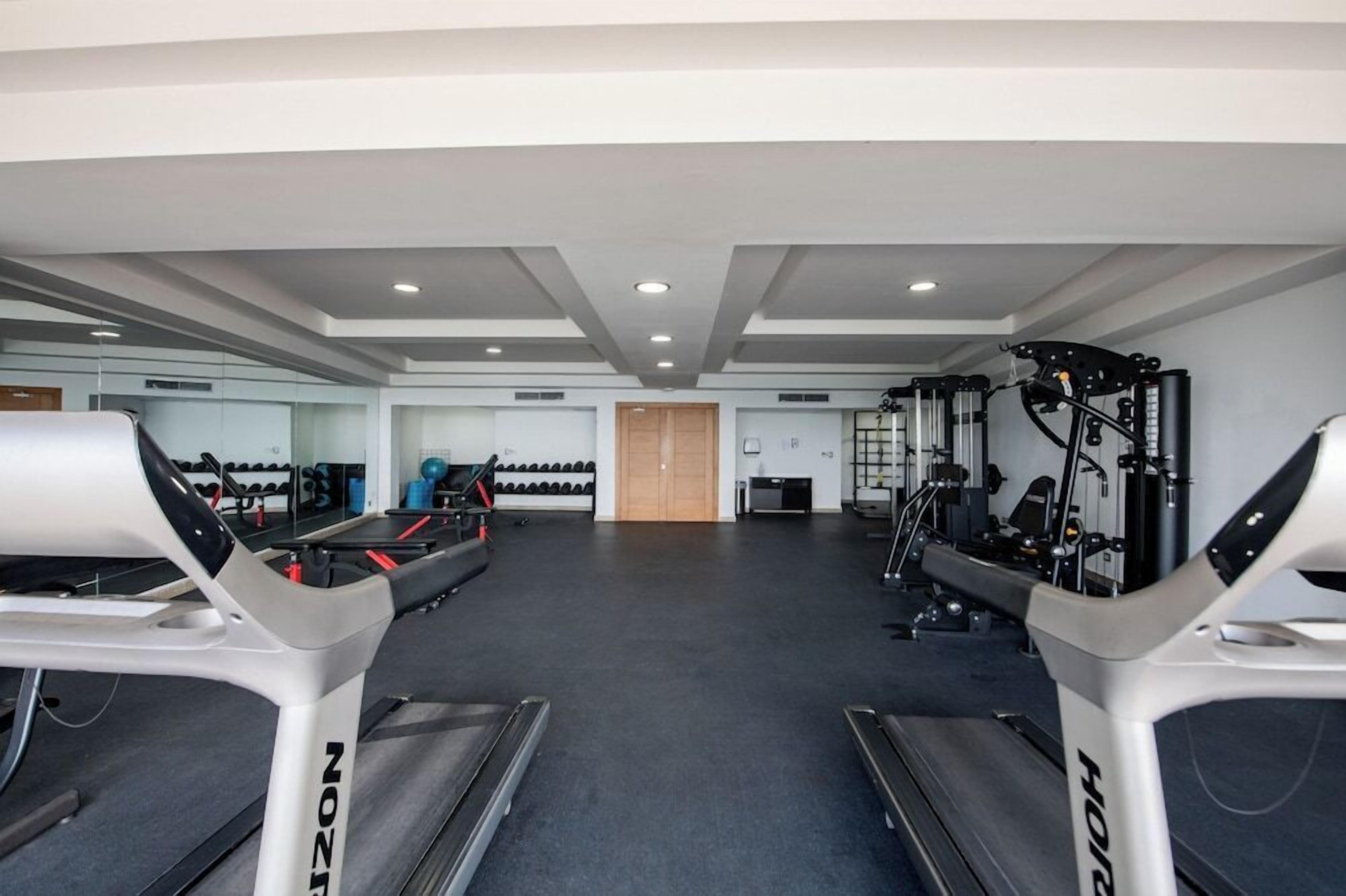 Ein Fitnessstudio mit Laufbändern, Krafttrainingsgeräten und Übungsbällen.