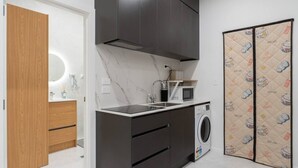 A compact kitchen with a microwave, sink, and washing machine, wooden cabinets, and a marble backsplash. - Central Modern Apartment - Easy Access Location (Auckland Central)