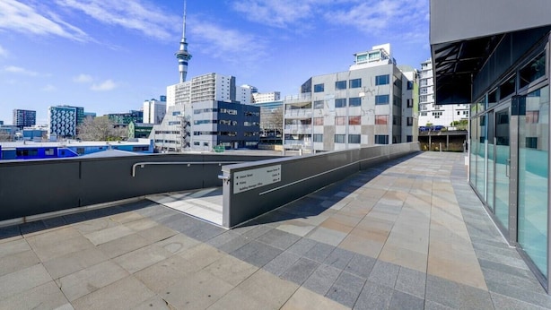 A rooftop terrace with a city skyline view, including a prominent tower. - Central Modern Apartment - Easy Access Location (Auckland Central)