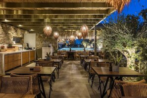 Ein Restaurant mit einer Steinwand, Holztischen und hängenden Lampen.