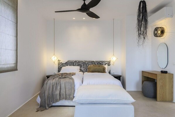 Ein modernes Schlafzimmer mit Bett, Nachttischen, Deckenventilator und Wandleuchte.