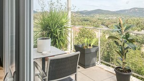A balcony with a table, chairs, and potted plants. - Appt proche plage et St-Tropez (Grimaud)