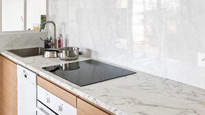 A modern kitchen with a stainless steel sink, a black induction cooktop, and a marble countertop. - Appt proche plage et St-Tropez (Grimaud)