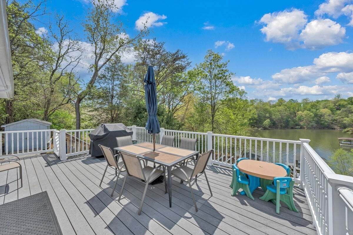 Une terrasse avec une table et des chaises, un barbecue et une vue sur un lac.