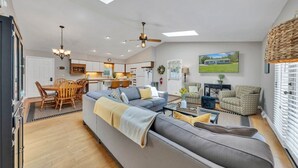 Ein modernes Wohnzimmer mit Sofa, Sesseln, einem Essbereich und einer Küche im Hintergrund.