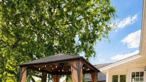 Une terrasse couverte avec une table et des chaises, un barbecue et des marches menant à la maison.