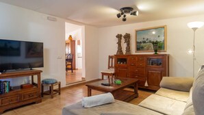 Ein Wohnzimmer mit Fernseher, Sofa, Couchtisch und Holzkabinent.