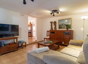 Ein Wohnzimmer mit Fernseher, Sofa, Couchtisch und Holzkabinent.