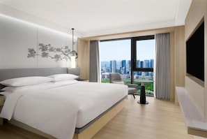 A modern hotel room with a large bed, a desk, a chair, a TV, and a city view. - Courtyard Sejong (Sejong)