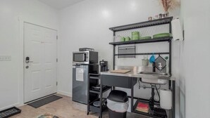 Una cocina compacta equipada con microondas, refrigerador y un lavamanos pequeño.