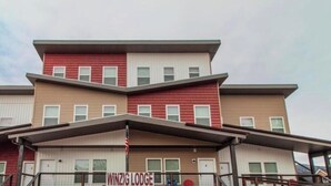 Un edificio de varios pisos con un llamativo letrero 'WINZIG LODGE', que presenta una fachada simétrica con una entrada central y un techo plano.