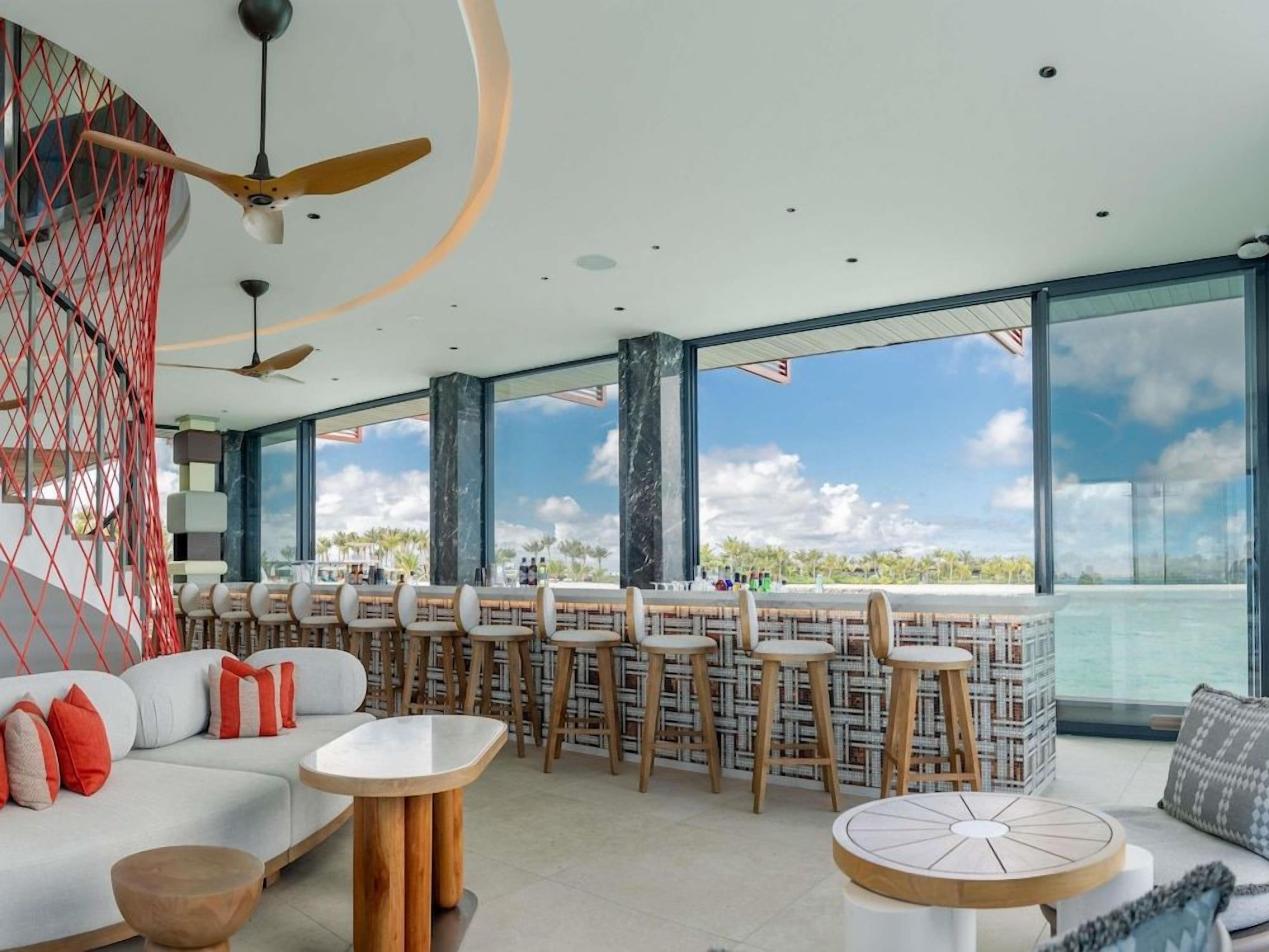 Et moderne loungeområde med bar, siddepladser og havudsigt.