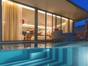 A modern hotel room with a large window, a bed, a seating area, and a pool. - SO/ Maldives (Emboodhoo Lagoon)
