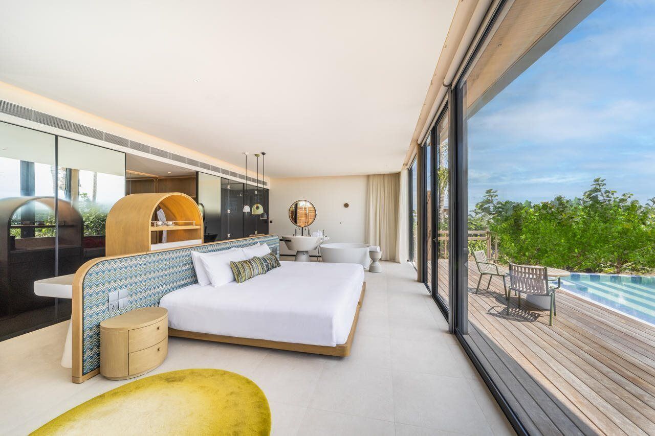 Una habitación de hotel moderna con una cama grande, un escritorio, un tocador y vistas a una piscina.