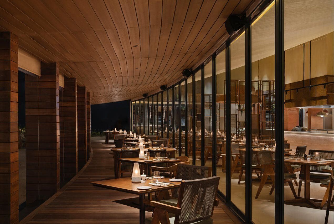 Un restaurante con suelo de madera, mesas dispuestas para comer y un techo curvo.