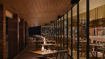 Un restaurante con suelo de madera, mesas dispuestas para comer y un techo curvo.