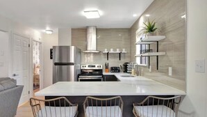 Una cocina moderna con una isla central, horno empotrado y electrodomésticos de acero inoxidable.