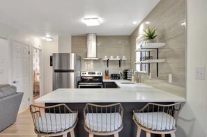 A modern kitchen with a central island, built-in oven, and stainless steel appliances. - Modern 5BR GameRoom, HotTub, FirePit + Lake Access (East Stroudsburg)