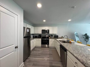 A modern kitchen with white cabinets, stainless steel appliances, and a granite countertop. - 3BR 2.5BA Fort Jackson | Fast Wi-Fi + Parking (Dentsville)
