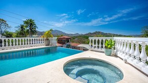 Piscina con jacuzzi, rodeada por una barandilla blanca, con vistas a la montaña al fondo.