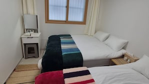 Une chambre d’hôtel comprenant un lit, une table de chevet, un miroir, un appareil de climatisation, une fenêtre avec des rideaux et une lampe sur pied.
