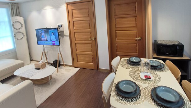 Un salon moderne avec un canapé, un téléviseur, une table à manger dressée avec de l’assiette et un four à micro-ondes.