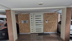 Un hall d’entrée propre, carrelé, doté d’une double porte, d’un petit panneau de commande et d’un dispositif de sécurité fixé au mur.