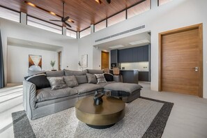 A modern living room with a sectional sofa, a round coffee table, and a large wooden door. - Space Botanica Modern Loft pool villa 29 Phuket-3 (159/29,3,Phuket,)