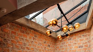 A brick interior with a staircase, a metal railing, and a ceiling light fixture. - 5Q House Chapinero (Bogotá)