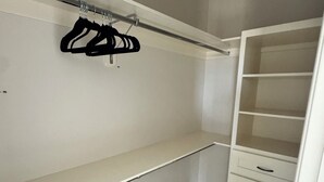 En rymlig klädkammare med öppna hyllor, en klädstång och en uppsättning lådor.