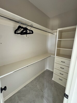 Ein begehbarer Kleiderschrank mit offenen Regalen, einer Kleiderstange und Schubladen.