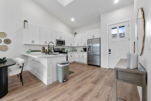 Una cocina moderna con armarios blancos, electrodomésticos de acero inoxidable y una isla central.