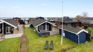 A row of modern, single-story cabins with large windows, a covered patio, and a grassy yard. - Gorgeous home in Otterup with WiFi (Otterup)