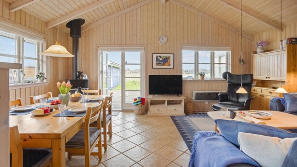A spacious living area with a dining table, sofa, TV, and wooden walls. - Gorgeous home in Otterup with WiFi (Otterup)