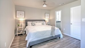 Ein Schlafzimmer mit Bett, Nachttischen, Deckenventilator und einer Tür.
