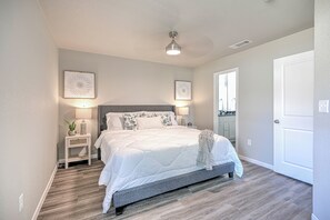 Ein Schlafzimmer mit Bett, Nachttischen, Deckenventilator und einer Tür.